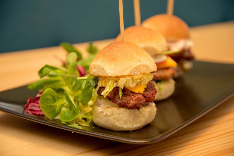 Mini hamburgers savoureux en gros plan avec de la salade sur la table de Bistros photo libre de droits Mini hamburgers savoureux en gros plan avec de la salade sur la table de Bistros photo libre de droits