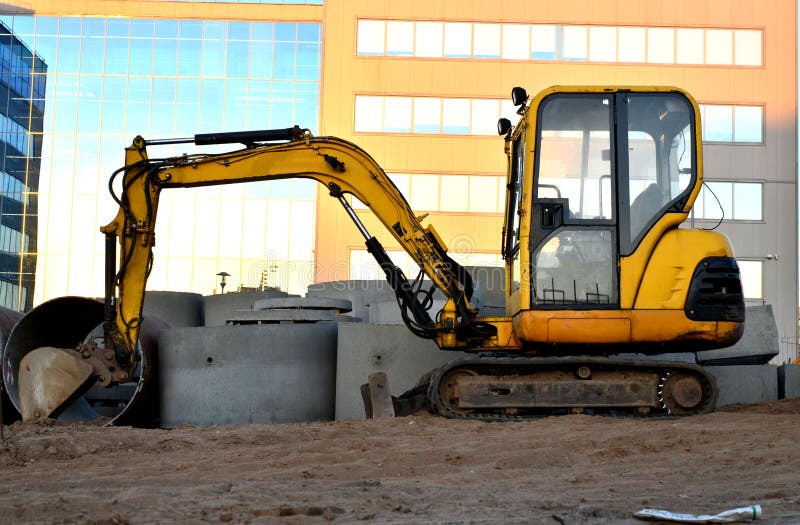 Mini m?quina escavadora em um canteiro de obras imagem de stock Mini m?quina escavadora em um canteiro de obras imagem de stock