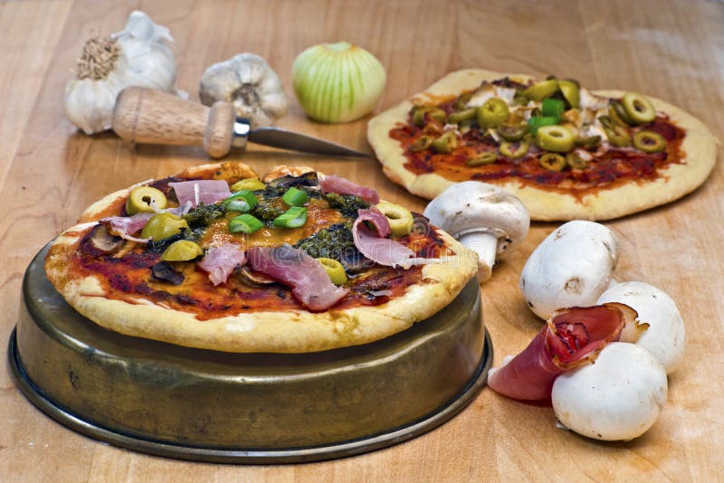 Mini- pizza med prosciutto, champinjoner, oliv, pesto och ost t royaltyfri fotografi Mini- pizza med prosciutto, champinjoner, oliv, pesto och ost t royaltyfri fotografi