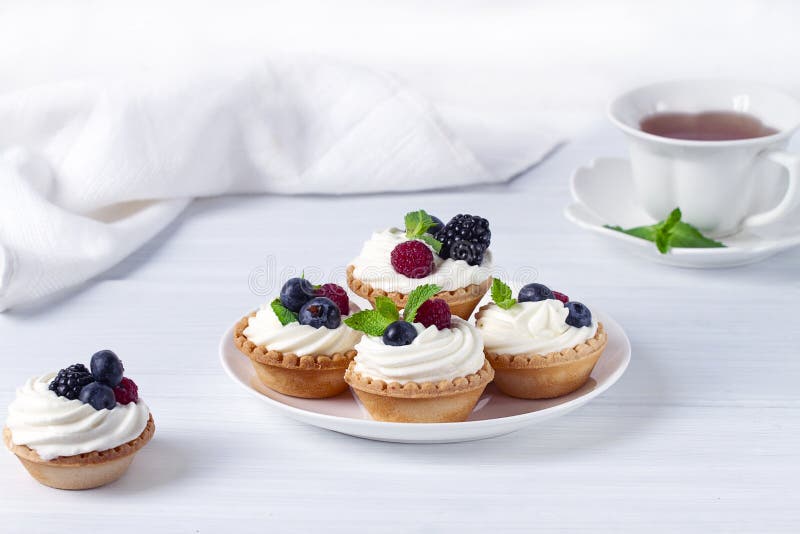 Mini tartlets with whipped cream and fresh berries, on a white table, blurred focus, horizontal, no people