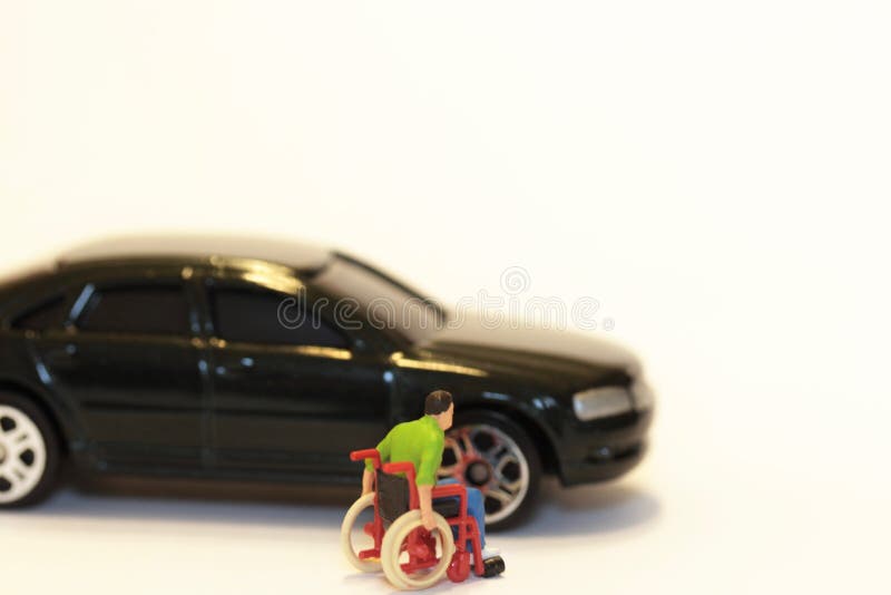 Miniatura de un hombre discapacitado en una silla de ruedas con un coche imagenes de archivo