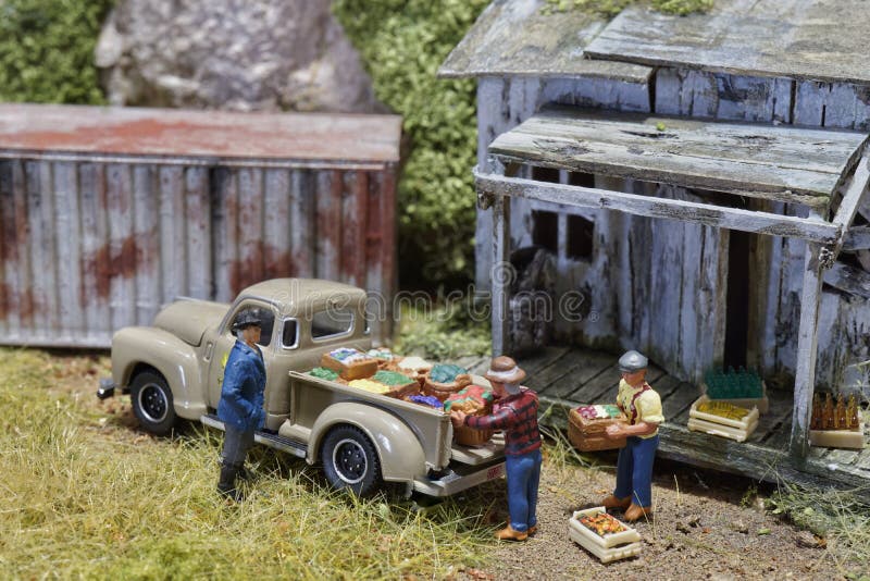 A miniatura do fazendeiro que olha os trabalhadores que levam bens do produto ao car pegara na fábrica do armazém de distribuiçã foto de stock A miniatura do fazendeiro que olha os trabalhadores que levam bens do produto ao car pegara na fábrica do armazém de distribuiçã foto de stock