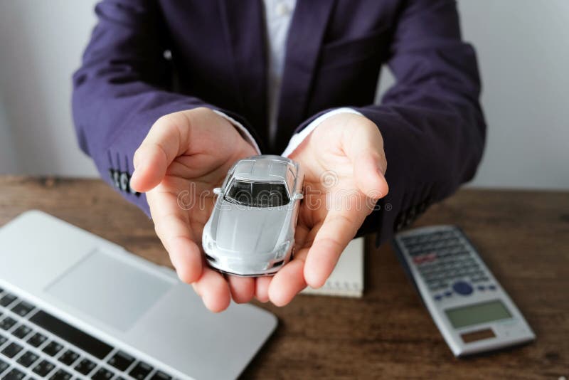 Miniature car model on hand with laptop and calculator on wooden royalty free stock image Miniature car model on hand with laptop and calculator on wooden royalty free stock image