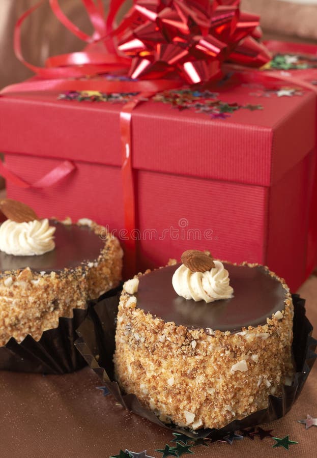 Miniaturní čokoládové pusinky koláče s krémem a mandlí a červené dárkové krabičky na pozadí.
