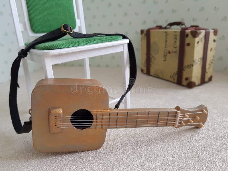 Miniature puppet guitar lies on a puppet chair royalty free stock photos