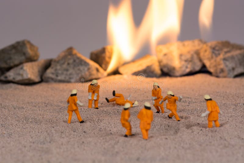 Miniature firemen at work near real fire stock images