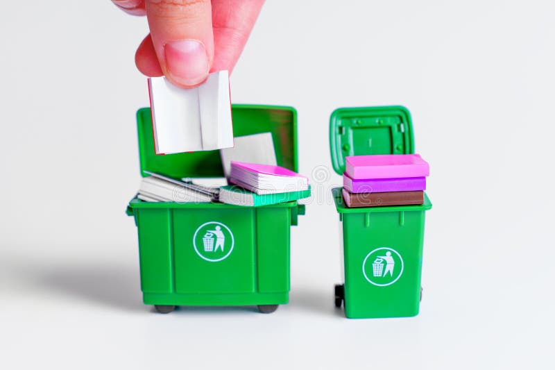 Miniature Hand Disposing Books in Green Trash Bins on White Background stock images