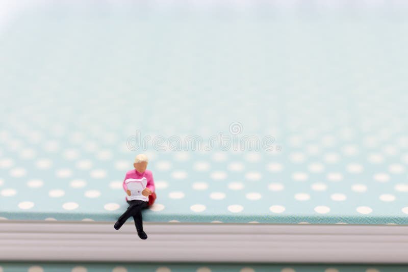 Miniature people : Businessman sitting on book and reading the newspaper. Image use for business concept royalty free stock images Miniature people : Businessman sitting on book and reading the newspaper. Image use for business concept royalty free stock images