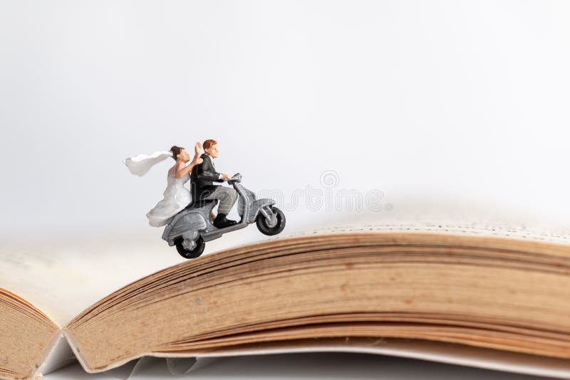 Miniature people : Couple riding the motorcycle on old book  , Valentine`s Day concept