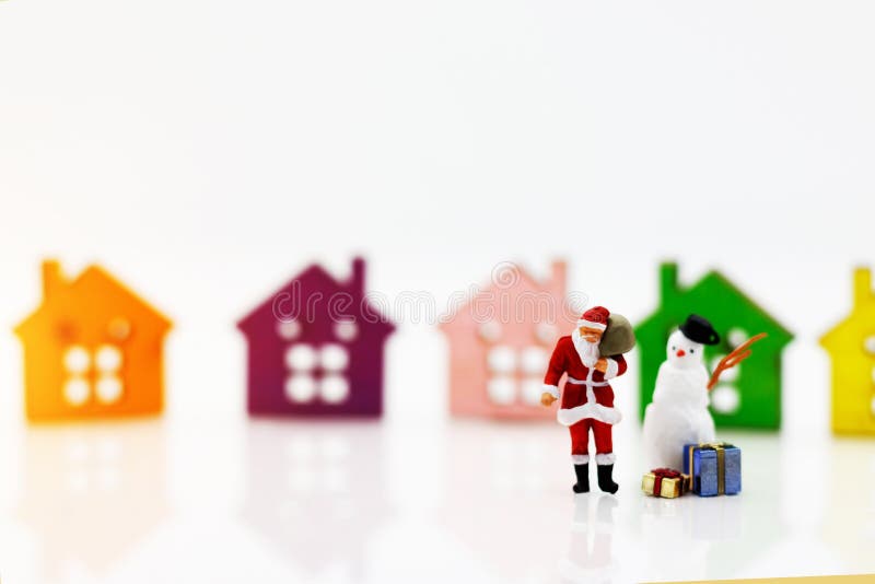 Miniature people: Santa Claus and snowman with gift standing before Wooden house model. Merry Christmas and Happy New Year concep stock photography Miniature people: Santa Claus and snowman with gift standing before Wooden house model. Merry Christmas and Happy New Year concep stock photography