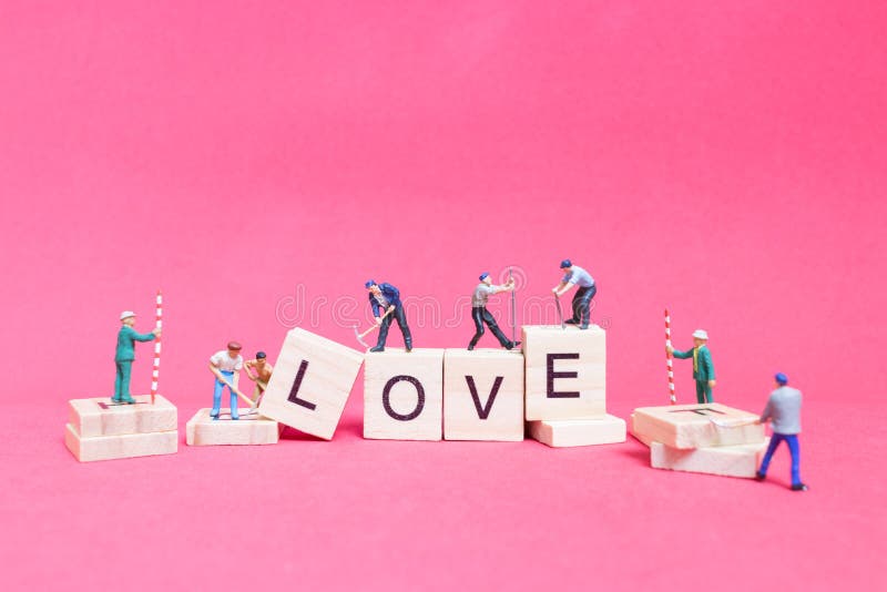 Miniature people : Worker team building word ` Love `