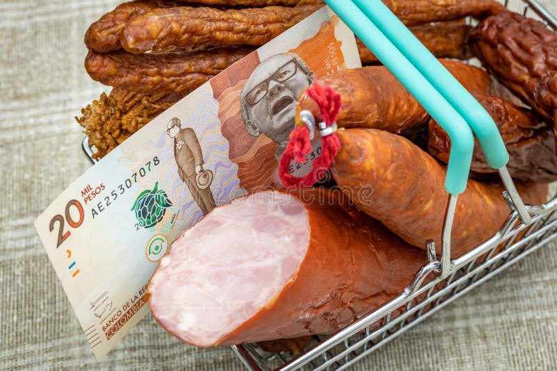 Miniature shopping cart full of all kinds of cold cuts with Colombian money, Concept, Rising meat prices during inflation
