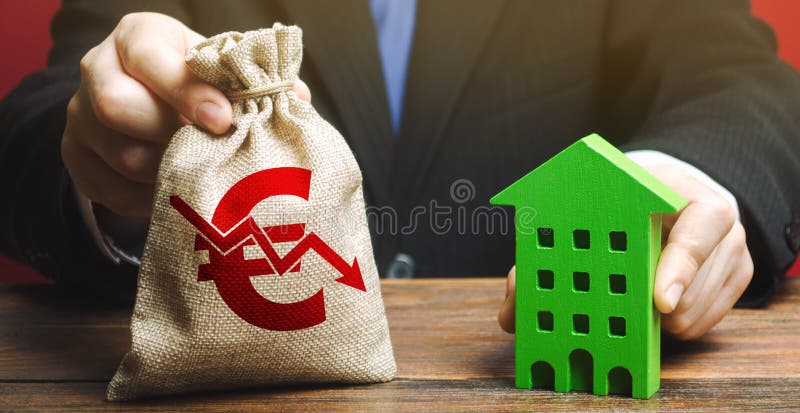 Miniature wooden house and a money bag with a down arrow in the hands of a businessman. The concept of low cost real estate. Lower royalty free stock photos Miniature wooden house and a money bag with a down arrow in the hands of a businessman. The concept of low cost real estate. Lower royalty free stock photos