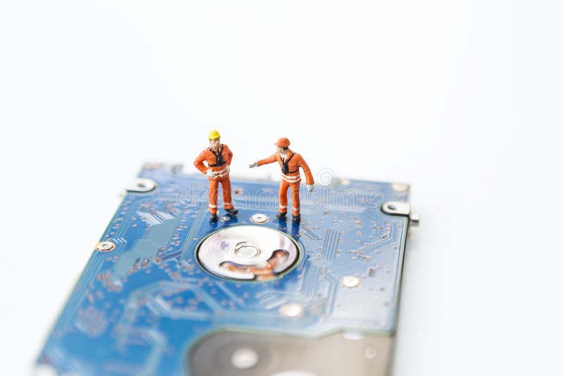 Miniature worker in safty suit on hard disk drive on white background, computer specialist, computer repair and maintenance, service and spare part