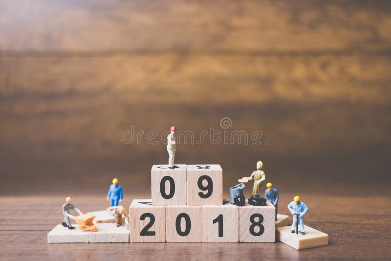 Miniature worker team building number on wooden block , Happy new year 2018