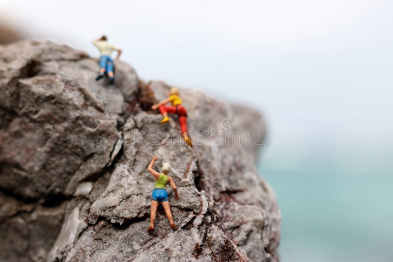 Miniaturleute: Bergsteiger, der oben beim Klettern der Herausforderung schaut