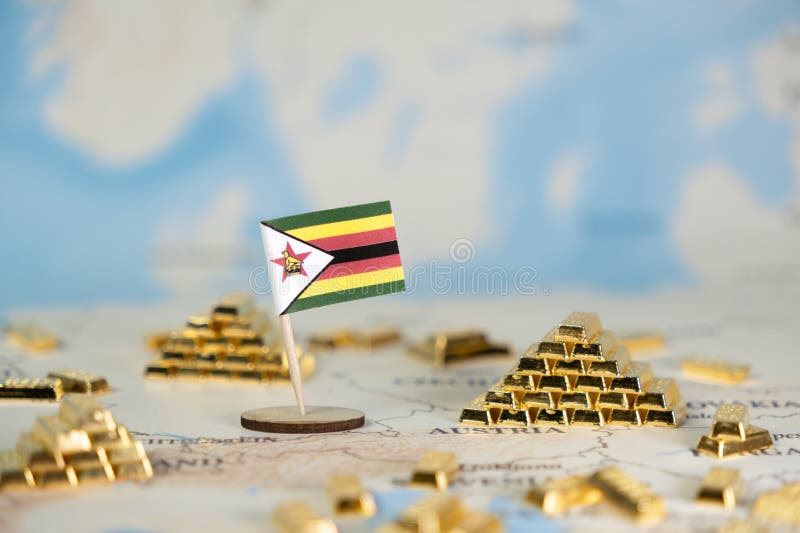 Miniaturowa flaga Zimbabwe znajduje się pośród licznych cennych złotych barów na zamazanej mapie świata przedstawiającej ekonomię obraz royalty free