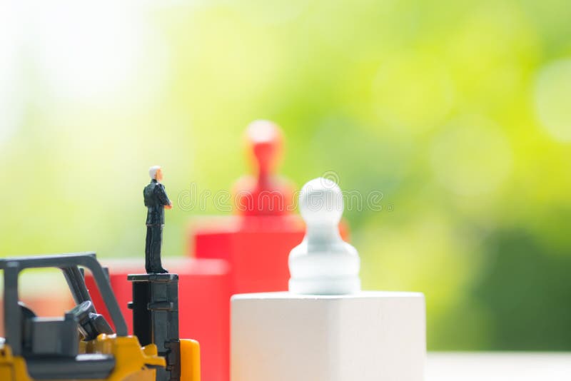 Miniaturowi ludzie biznesmen pozycji na zabawkarskim żółtym forklift fotografia stock Miniaturowi ludzie biznesmen pozycji na zabawkarskim żółtym forklift fotografia stock