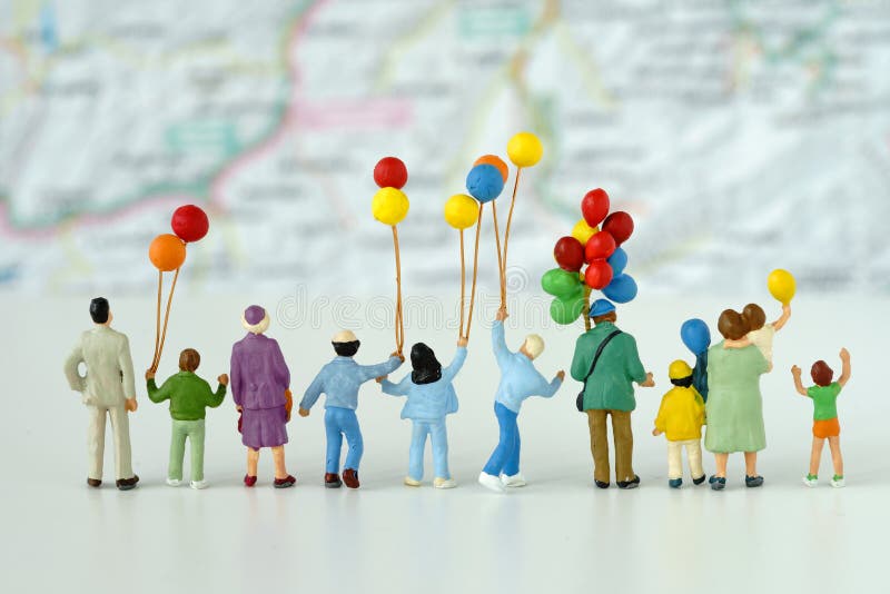 Miniaturowi ludzie patrzeje mapę w t z rodzinnym mienie balonem obraz stock Miniaturowi ludzie patrzeje mapę w t z rodzinnym mienie balonem obraz stock