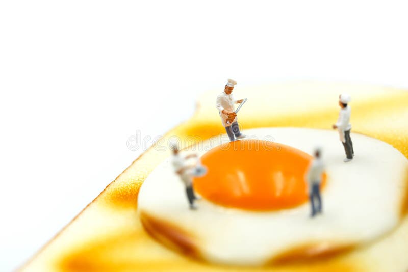 Miniaturowi ludzie: Szef kuchni na grzanka chlebie z jajkiem na białym backgro obraz stock Miniaturowi ludzie: Szef kuchni na grzanka chlebie z jajkiem na białym backgro obraz stock