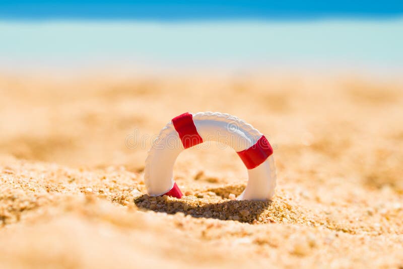 Miniaturowy Lifebuoy W piasku zdjęcie stock Miniaturowy Lifebuoy W piasku zdjęcie stock