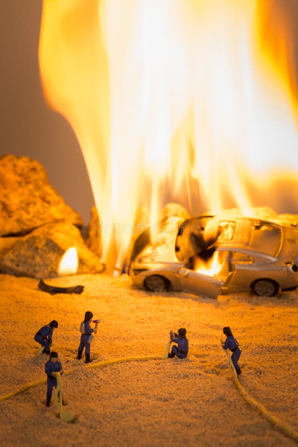 Miniatuurbrandbestrijders bij een scène van het autoongeval in vlammen royalty-vrije stock fotografie Miniatuurbrandbestrijders bij een scène van het autoongeval in vlammen royalty-vrije stock fotografie