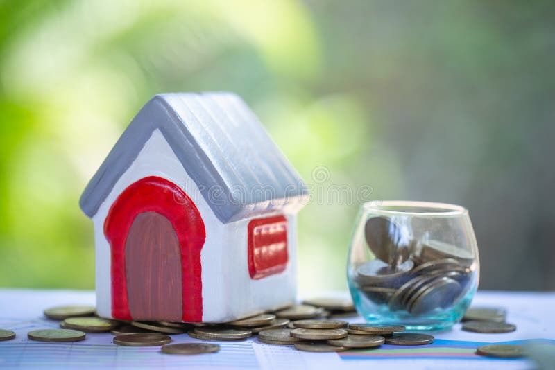 Miniatuurhuizen onder stapel van muntstukken, het Huisvestende plan van de de industriehypotheek en de woonstrategie van de belas stock afbeelding Miniatuurhuizen onder stapel van muntstukken, het Huisvestende plan van de de industriehypotheek en de woonstrategie van de belas stock afbeelding