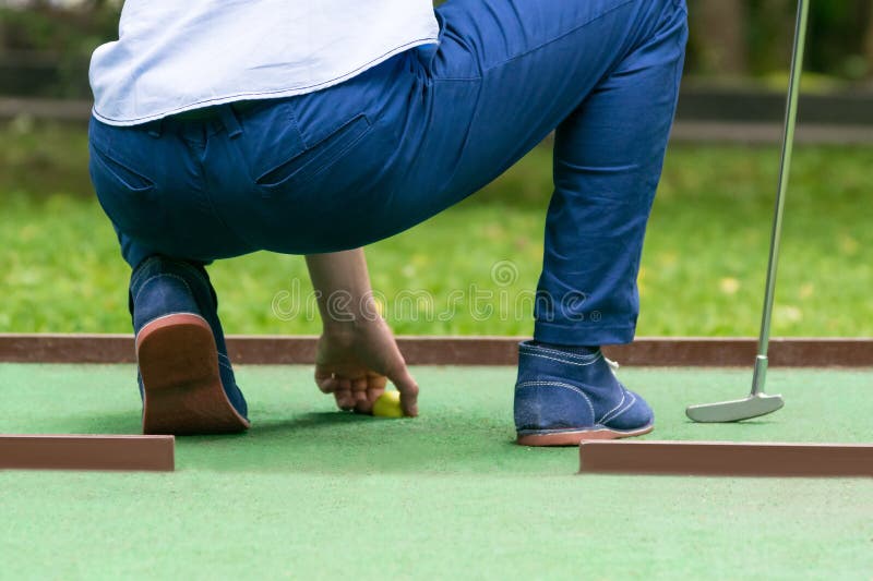 Minigolf-Spieler zieht einen gelben Ball das Loch, hintere Ansicht, Nahaufnahme heraus stockfotos Minigolf-Spieler zieht einen gelben Ball das Loch, hintere Ansicht, Nahaufnahme heraus stockfotos