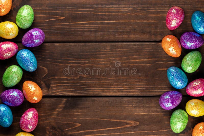 Minimal easter concept with colored easter eggs as a frame. Wooden background with copy space, top view royalty free stock images
