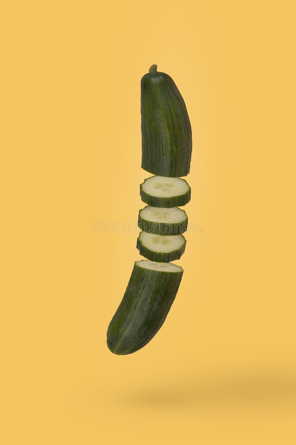 Minimal idea with fresh sliced cucumber floating in air isolated on pastel yellow background. Diet, vitamins, vegan and healthy