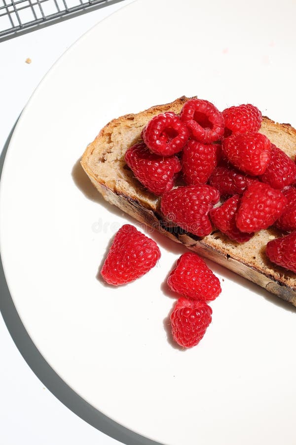 Minimal Raspberry Toast Flat Lay. Flat lay of rustic toast topped with vibrant red raspberries. A clean, modern composition captured in daylight.