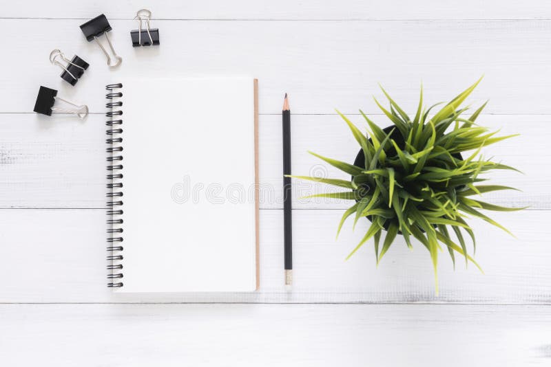 White office desk wooden table background with open mock up notebooks and pens and plant.