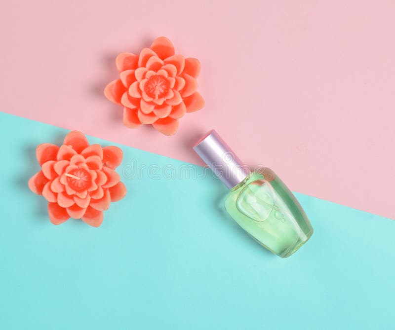 Minimalismo piano di disposizione di una bottiglia di profumo e delle candele sotto forma di fiori su un fondo pastello fotografia stock libera da diritti Minimalismo piano di disposizione di una bottiglia di profumo e delle candele sotto forma di fiori su un fondo pastello fotografia stock libera da diritti