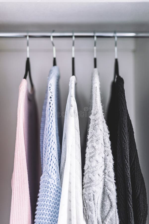 Minimalist capsule wardrobe selection of womenswear sweaters and cardigans with matching hangers shot at shallow depth of field stock photos Minimalist capsule wardrobe selection of womenswear sweaters and cardigans with matching hangers shot at shallow depth of field stock photos
