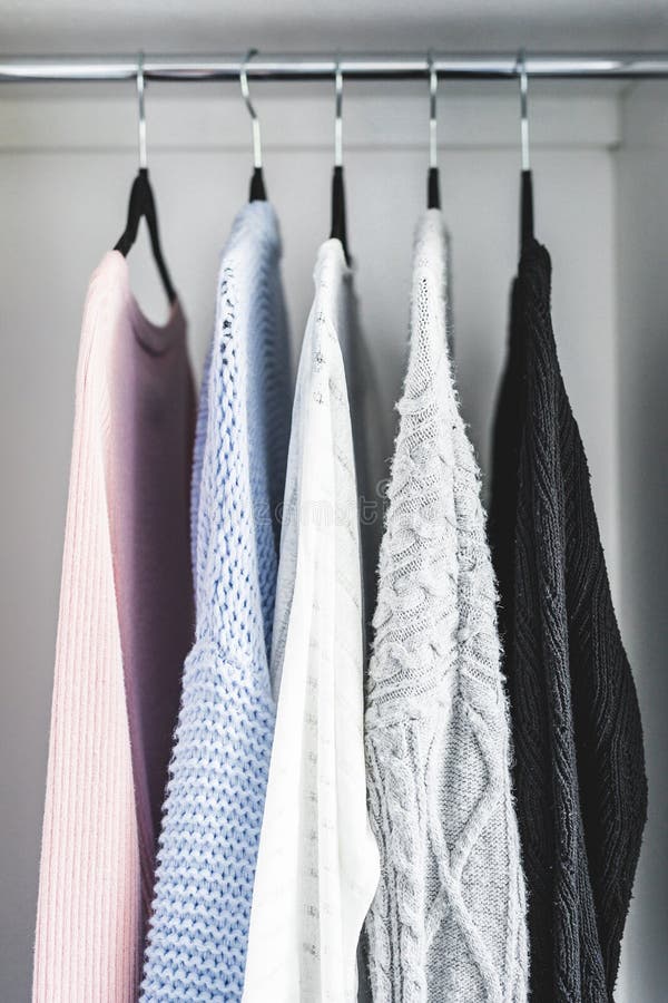 Minimalist capsule wardrobe selection of womenswear sweaters and cardigans with matching hangers shot at shallow depth of field royalty free stock photos Minimalist capsule wardrobe selection of womenswear sweaters and cardigans with matching hangers shot at shallow depth of field royalty free stock photos