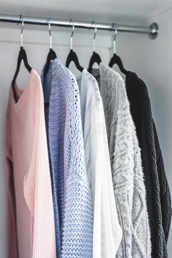Minimalist capsule wardrobe selection of womenswear sweaters and cardigans with matching hangers shot at shallow depth of field stock photo Minimalist capsule wardrobe selection of womenswear sweaters and cardigans with matching hangers shot at shallow depth of field stock photo