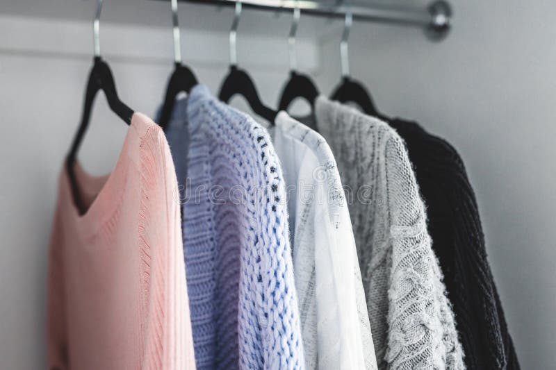 Minimalist capsule wardrobe selection of womenswear sweaters and cardigans with matching hangers shot at shallow depth of field royalty free stock photo Minimalist capsule wardrobe selection of womenswear sweaters and cardigans with matching hangers shot at shallow depth of field royalty free stock photo