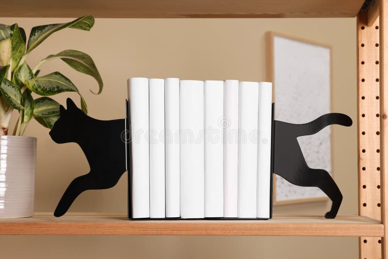 Minimalist cat shaped bookends with books and plant on shelf indoors