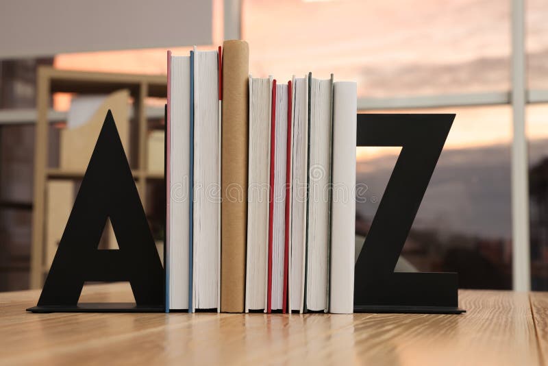 Minimalist letter bookends with books on wooden table indoors