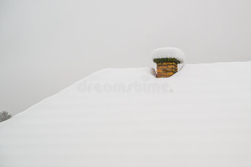 Minimalist snow-buried brick chimney protruding from heavy snowdrift stock photo
