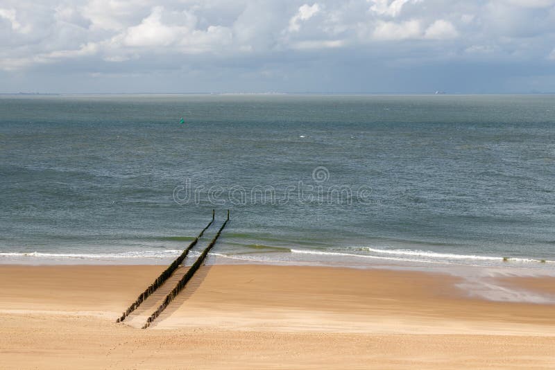 Minimalist view of the Dutch coastline with the water breakers during low tide of the North sea under a dramatic sky