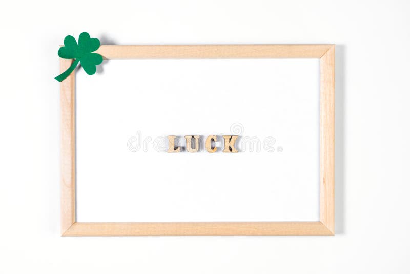 Minimalistic flatlay for St. Patrick`s Day. Shamrock and frame on a white background. Happy Irish holiday, symbols of good luck