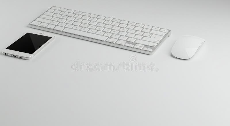 A minimalistic white desktop setup featuring a wireless keyboard and mouse. The keyboard has a sleek, compact design with chiclet-style keys and a minimalistic layout. Nearby, a smartphone with a black screen and white frame lies flat on the smooth, light-colored surface, suggesting a modern and clean workspace. The arrangement provides an uncluttered aesthetic with cohesive color coordination, indicating a focus on simplicity and functionality in the design of tech accessories.