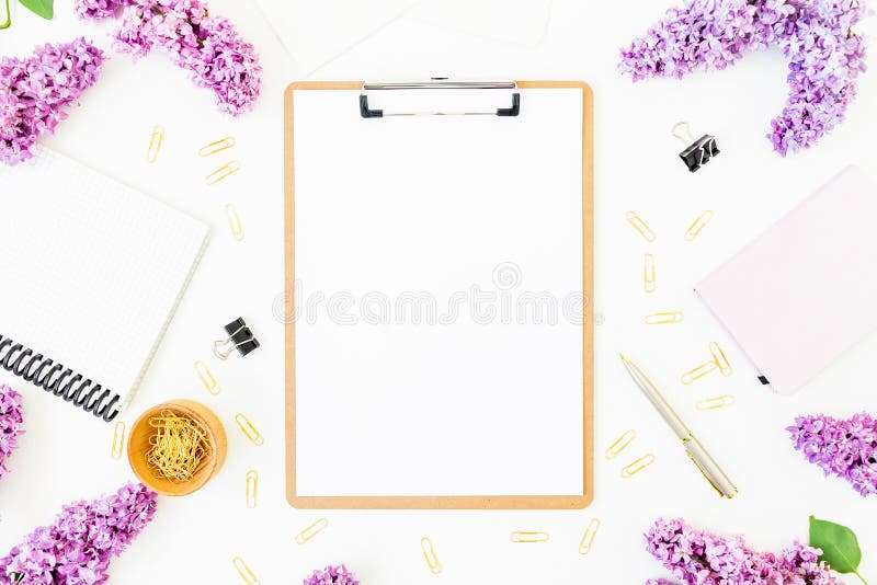 Minimalistic workspace with clipboard, notebook, pen, lilac and accessories on white background. Flat lay, top view. Beauty blog c