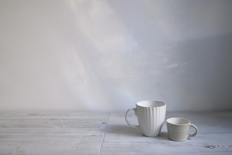 Minimalistic Scandinavian style. Two cups of coffee or tea of different sizes for two on on the table. Empty space. Minimalistic Scandinavian style. Two cups of coffee or tea of different sizes for two on on the table. Empty space