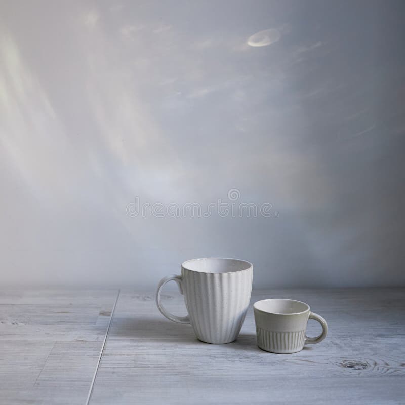 Minimalistic Scandinavian style. Two cups of coffee or tea of different sizes for two on on the table. Empty space. Square frame. Minimalistic Scandinavian style. Two cups of coffee or tea of different sizes for two on on the table. Empty space. Square frame