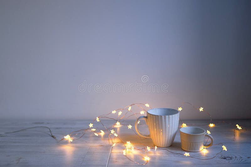 Minimalistic Scandinavian style. Two cups of coffee or tea of different sizes for two and garland on on the table. Empty space. Minimalistic Scandinavian style. Two cups of coffee or tea of different sizes for two and garland on on the table. Empty space