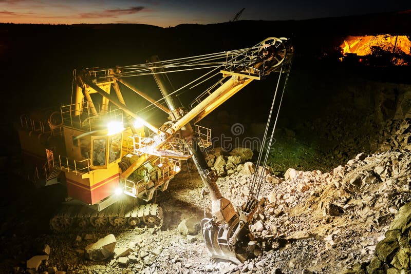 Mining industry. Heavy excavator digging granite rock or iron ore at dusk construction opencast quarry. Mining industry. Heavy excavator digging granite rock or iron ore at dusk construction opencast quarry.