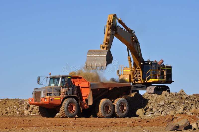 Mining excavator loading a truck in a open pit quarry mine. Mining excavator loading a truck in a open pit quarry mine