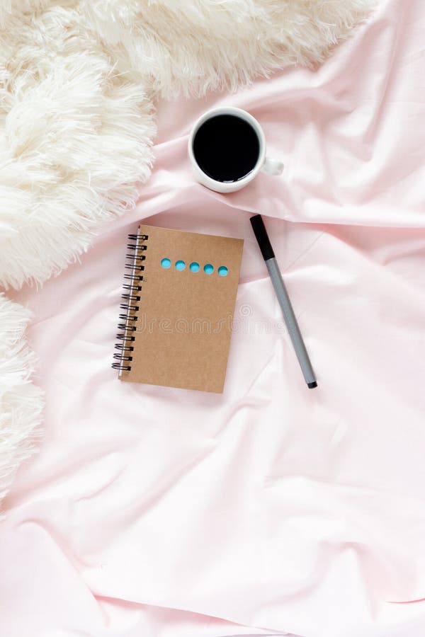 Ministerio del Interior en cama con la taza de café, libreta de Kraft, pluma en los linos rosados foto de archivo libre de regalías Ministerio del Interior en cama con la taza de café, libreta de Kraft, pluma en los linos rosados foto de archivo libre de regalías